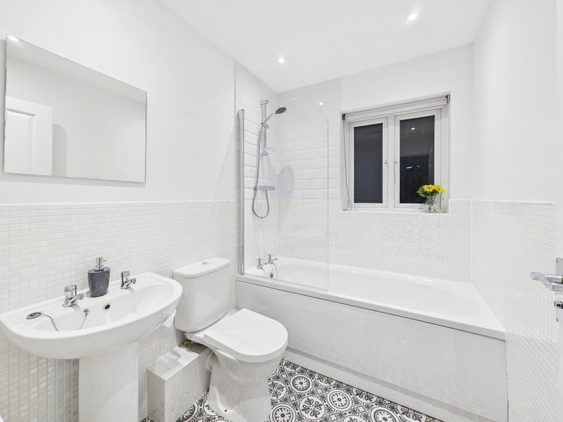 Modern white bathroom with pedestal sink, toilet, bathtub, shower enclosure and mirror