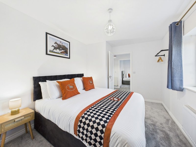 Modern bedroom with black bed, white bedding, orange decorative pillows and geometric throw
