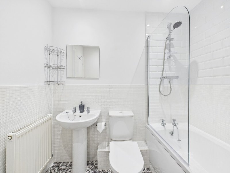 Modern white bathroom with pedestal sink, toilet, shower enclosure and mirror