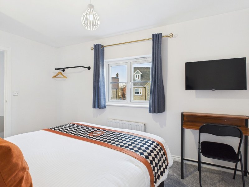 Modern bedroom with double bed, wall-mounted TV, window with blue curtains, and pendant light