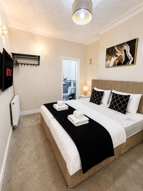Modern bedroom with double bed, black throw, patterned cushions and wall art