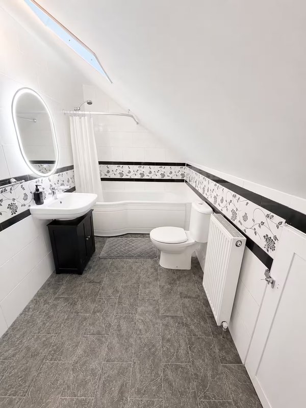 Modern bathroom with white sink, toilet, mirror, and grey floor tiles
