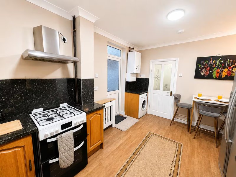 Kitchen with gas cooker, washing machine, dining table and chairs, wood flooring