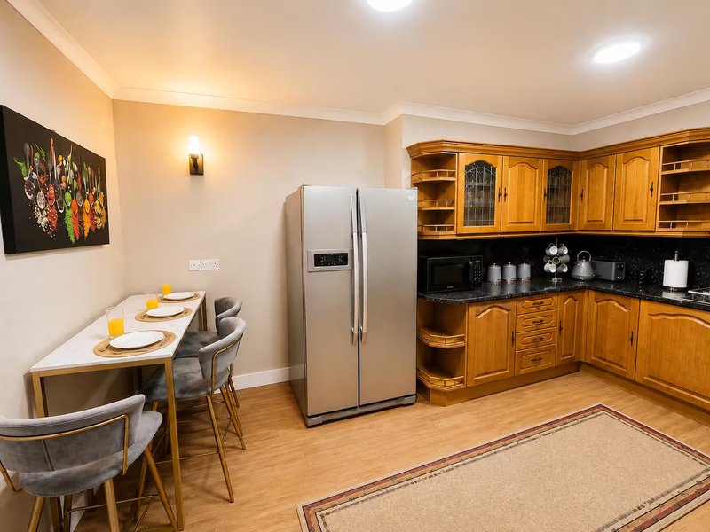 Modern kitchen with wooden cabinetry, stainless steel fridge, dining table with place settings