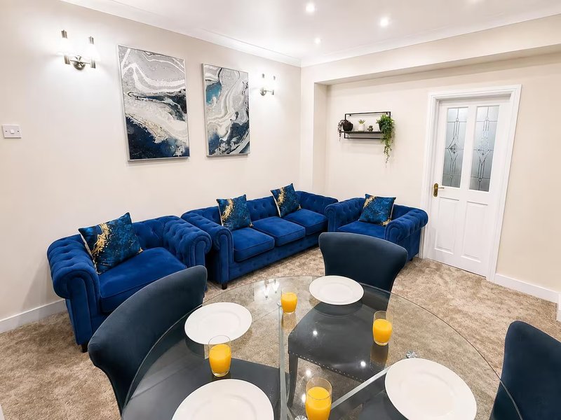Modern living room with blue velvet sectional sofa, black accent chairs, glass coffee table and wall art