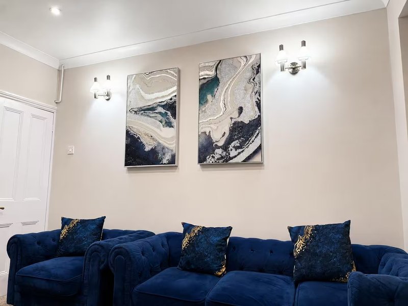 Modern living room with blue velvet sofa, decorative cushions, and abstract wall art