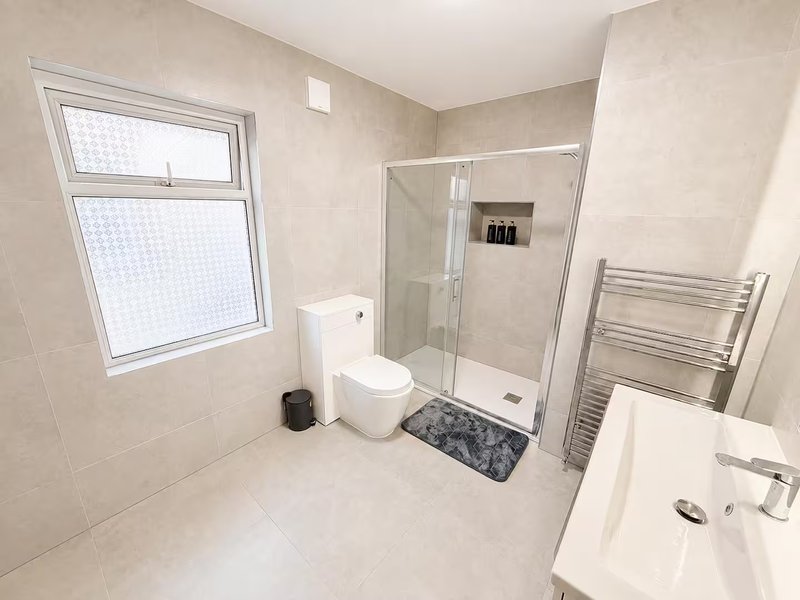 Modern bathroom with walk-in shower, toilet, sink, heated towel rail and window