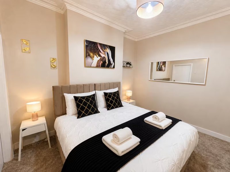 Modern bedroom with grey upholstered bed, white bedding, black decorative pillows and runner