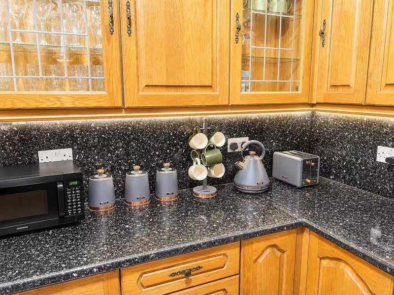 Kitchen with wooden cabinets, granite countertop, microwave, and decorative items