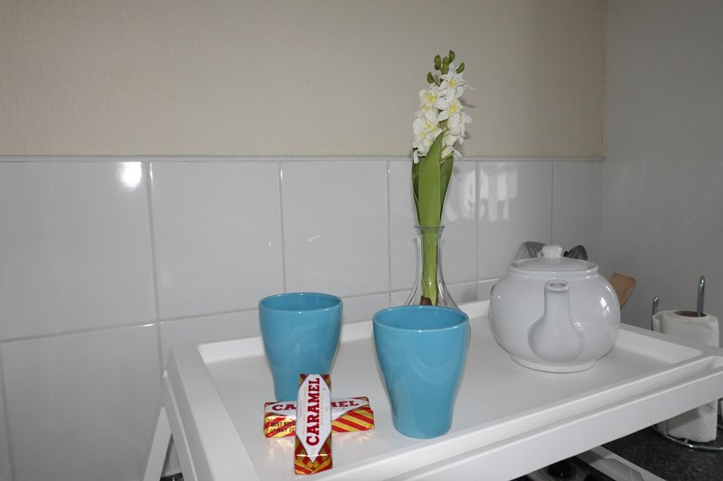 Bathroom counter with white tiles, blue cups, white flowers in vase, and toiletries