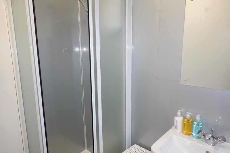 Bathroom with shower enclosure, sink counter with toiletries and products