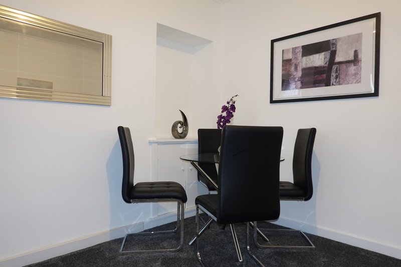 Modern dining area with black round table, two black chairs, and wall art