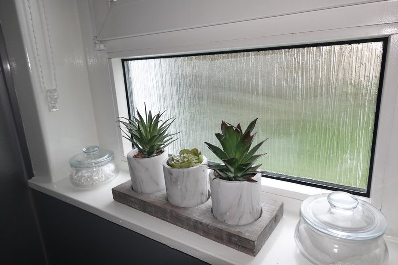 Windowsill with potted succulents, glass containers, and white ceramic lids