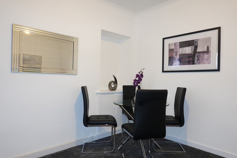 Modern dining area with black table, black chairs, mirror and framed artwork on walls
