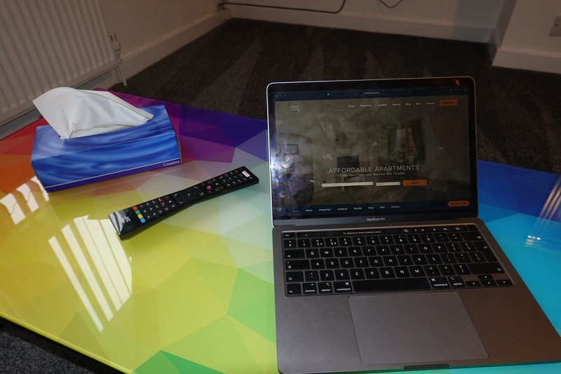 Desk with laptop, remote control, colorful geometric surface, and tissue box