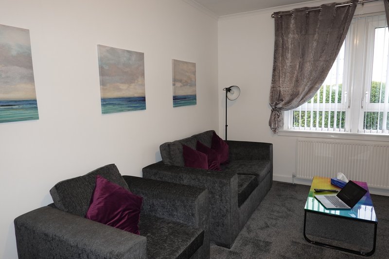 Living room with dark grey modular sofa, burgundy cushions, abstract seating area with floor lamp and window
