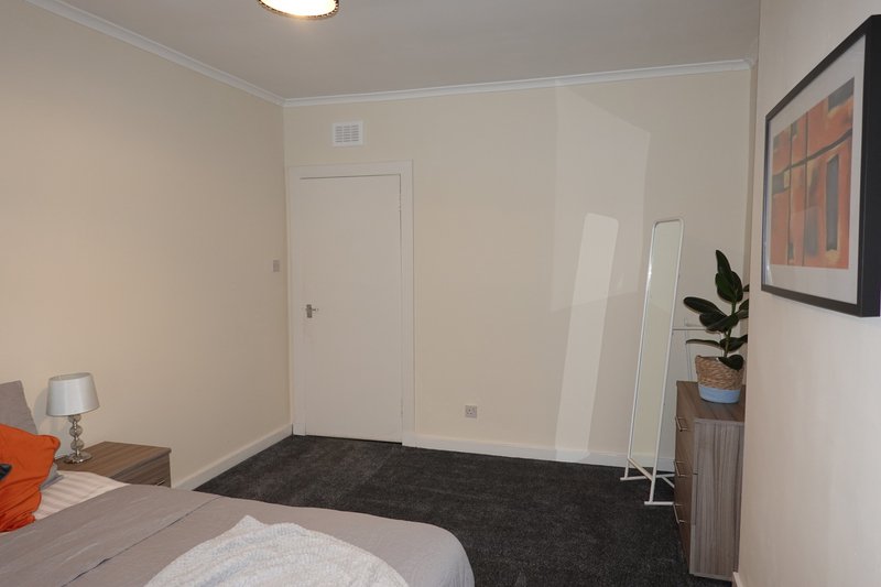 Bedroom with double bed, dark floor, white doors, potted plant and framed artwork
