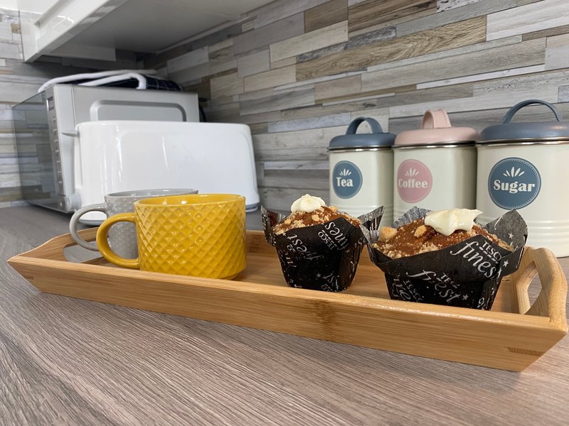 Kitchen counter with organized storage containers, yellow mug, and small appliances on wooden tray