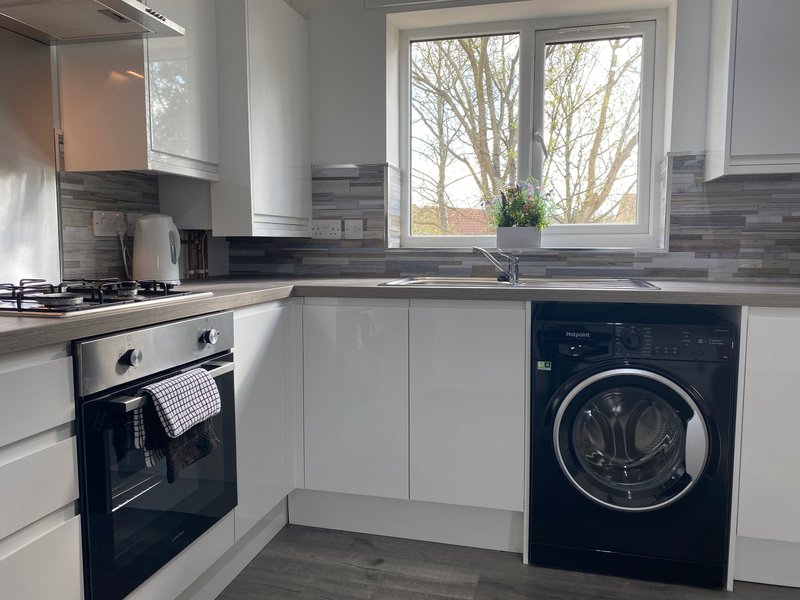 Modern kitchen with white cabinetry, black appliances, and window overlooking bare trees