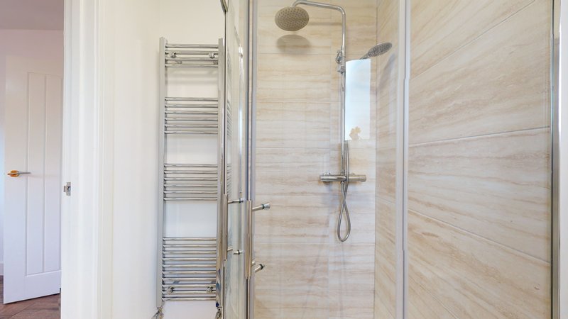 Modern bathroom with enclosed shower cubicle, heated towel rail and tiled walls
