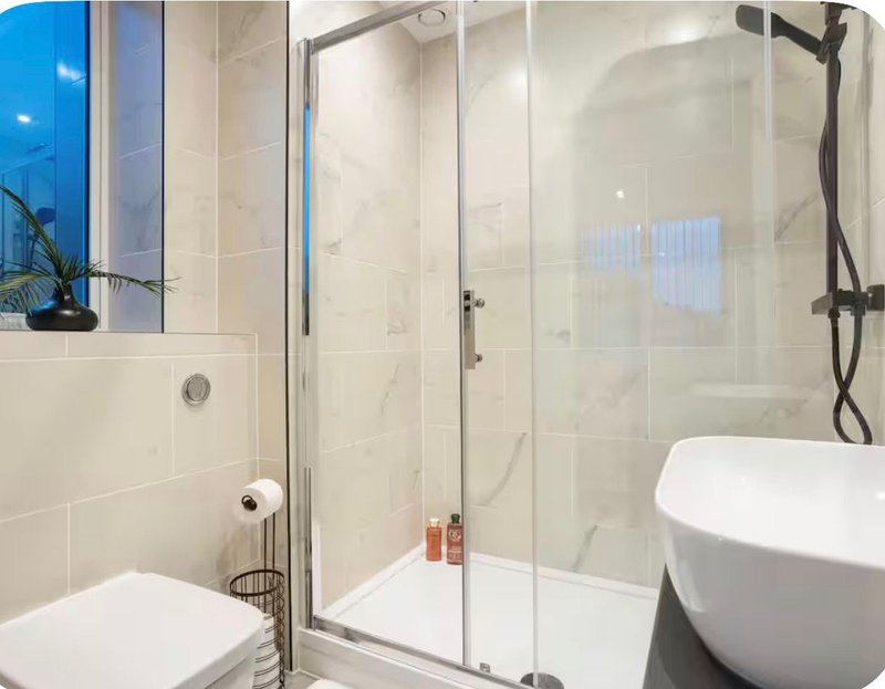 Modern bathroom with walk-in shower, freestanding tub, toilet and marble-effect tiling