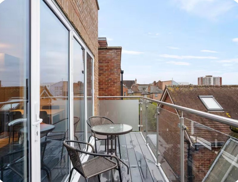 Rooftop terrace with seating, glass doors, brick buildings and city skyline views