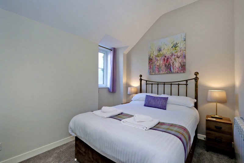 Modern bedroom with double bed, black headboard, bedside lamps and floral wall art