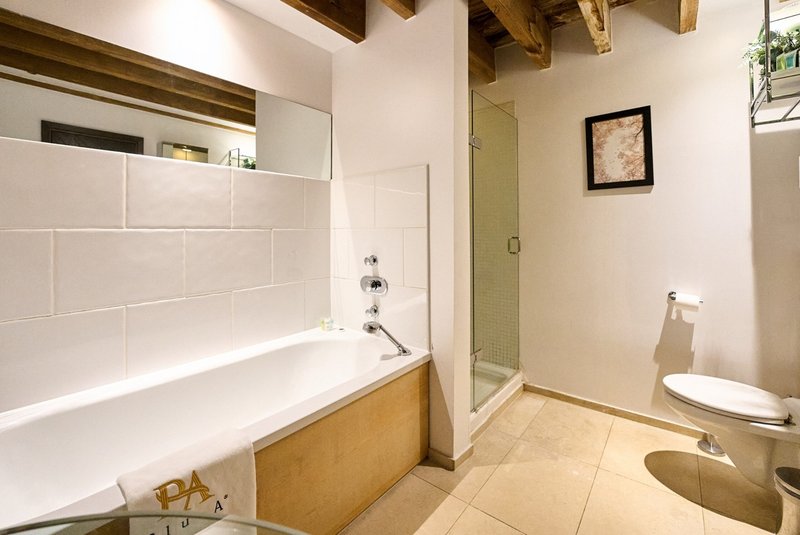Modern bathroom with bathtub, shower enclosure, toilet, and wooden accents