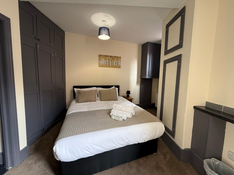 Bedroom with double bed, dark wardrobe, ceiling light and framed wall art