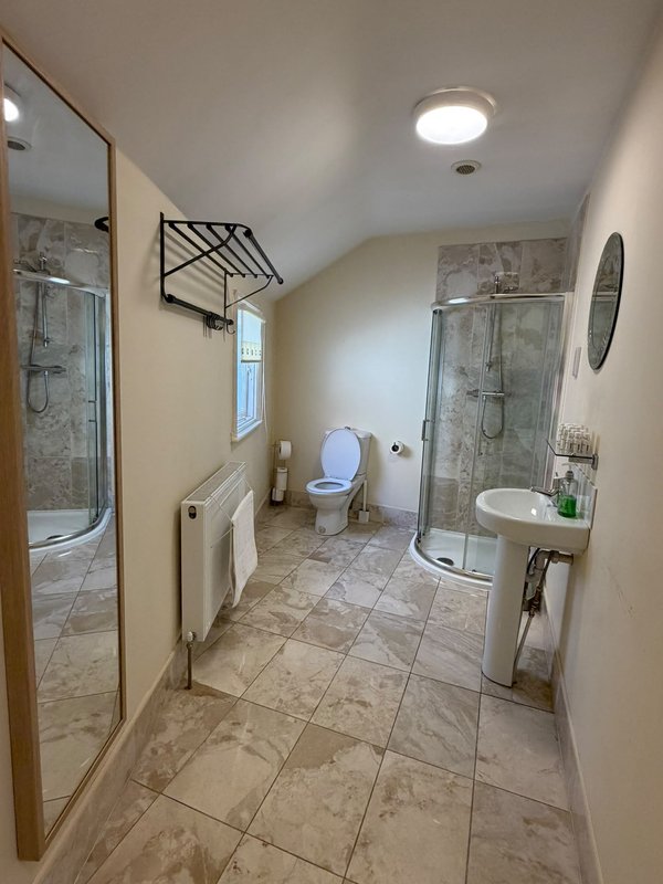 Spacious bathroom with dual walk-in showers, toilet, vanity sink and tiled flooring