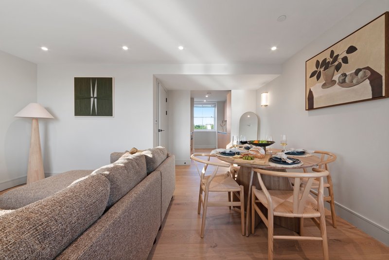 Open-plan living and dining area with grey sofa, wooden dining table, chairs, and pendant lamp