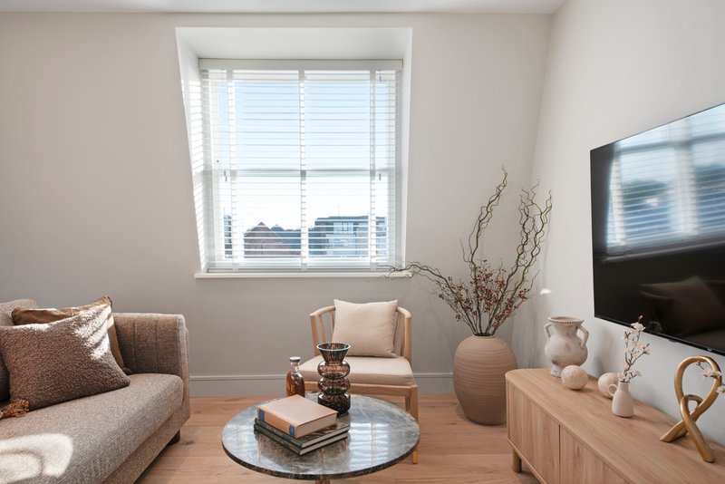 Modern living room with grey sofa, round coffee table, armchair and city view window