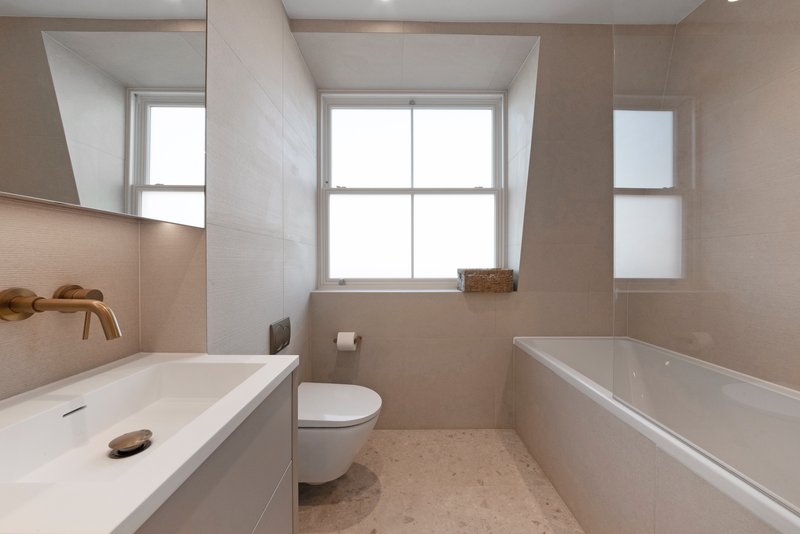 Modern bathroom with double sink vanity, bathtub, toilet, and large window