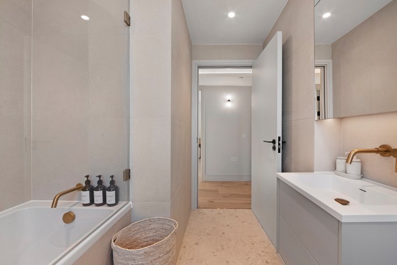 Modern bathroom with bathtub, white vanity, sink, toiletries and woven basket