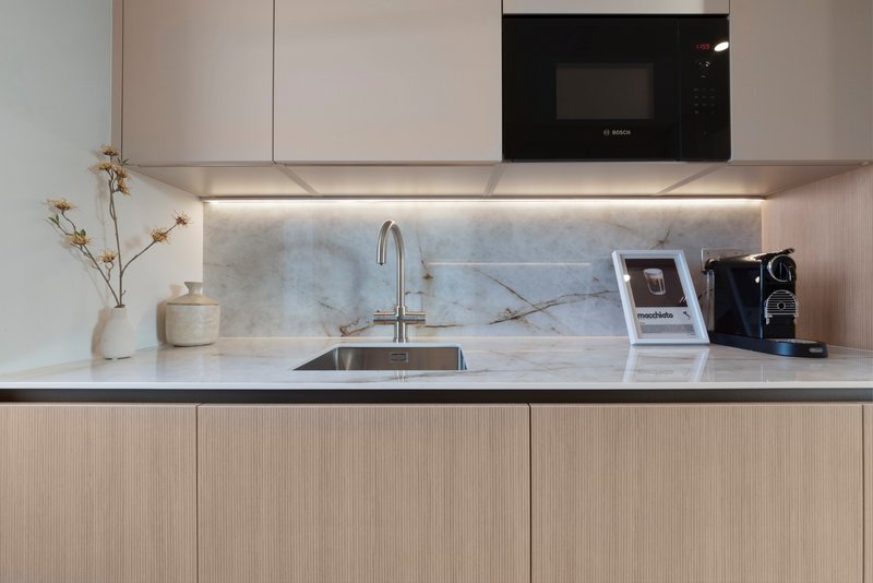 Modern kitchen with marble backsplash, integrated microwave, and minimalist countertop styling