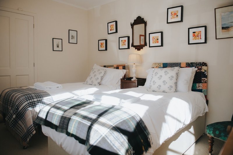 Bright bedroom with two single beds, patterned throws, framed artwork on walls