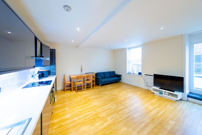 Open-plan apartment with modern kitchen, wooden flooring, blue sofa and dining area