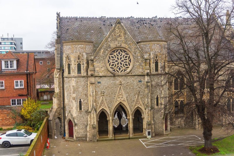 Historic stone church building with Gothic architecture, rose window and arched entrances