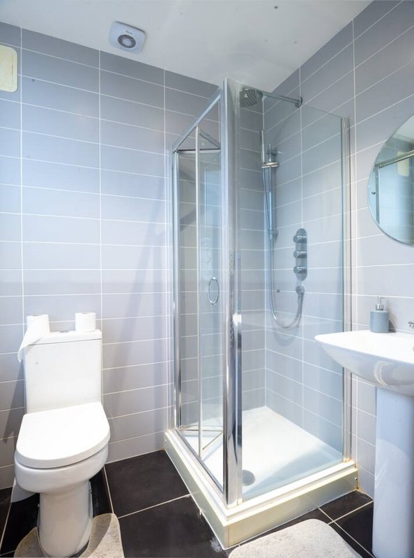 Modern bathroom with walk-in shower, toilet, pedestal sink and tiled walls