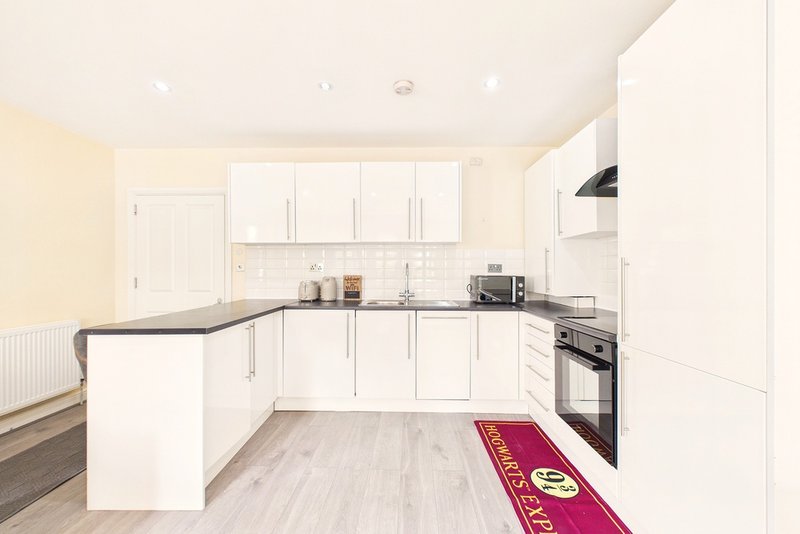 Modern white kitchen with island, built-in appliances, and light wood flooring