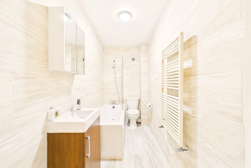 Modern bathroom with cream tile walls, wooden vanity, shower enclosure and heated towel rail