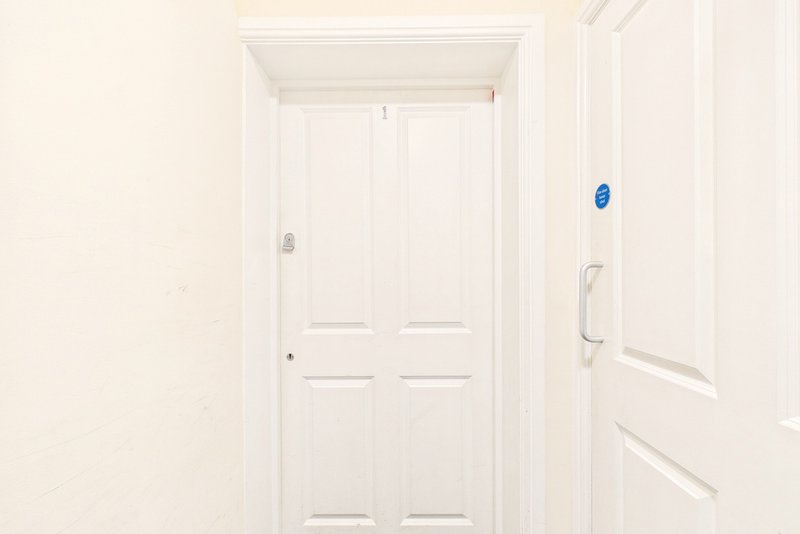 White hallway with closed double doors and light switch on wall
