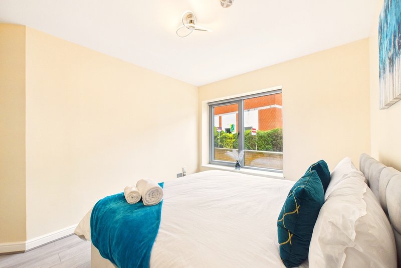 Bright bedroom with twin beds, rolled towels, teal throws and garden view window