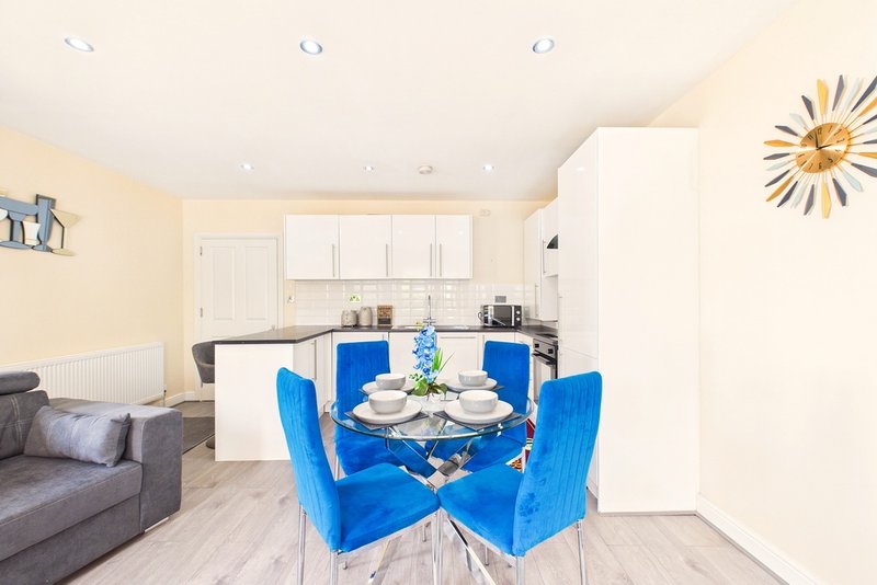 Open-plan kitchen and dining area with blue chairs, round table, and cream cabinetry
