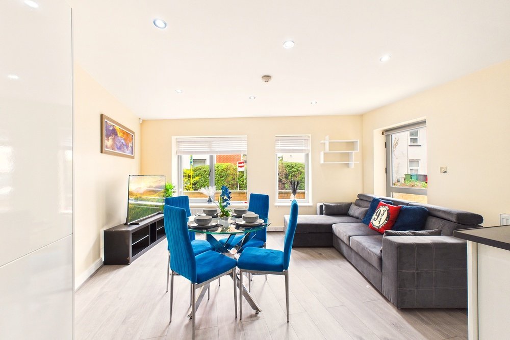 Open-plan living and dining area with blue chairs, dark sofa, and garden view through patio doors