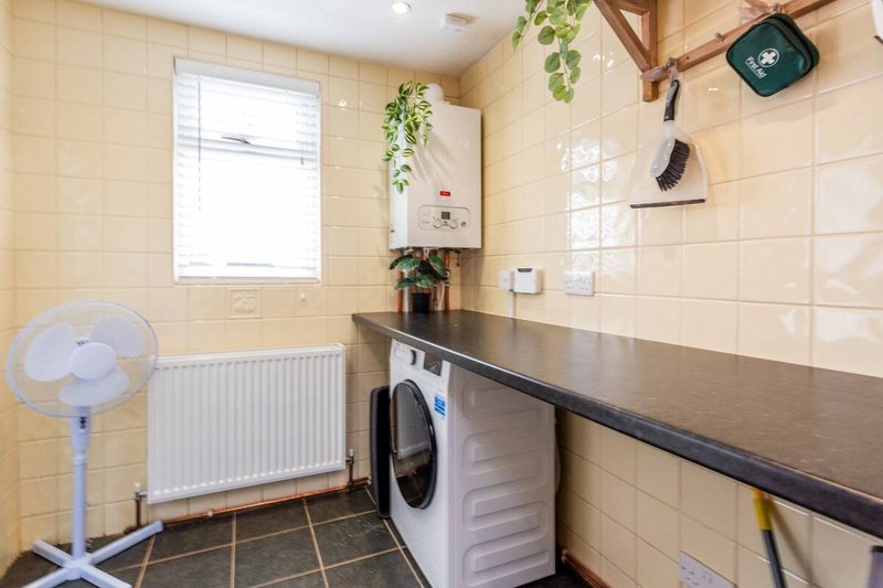 Utility room with washing machine, counter space, window, radiator and hanging plants
