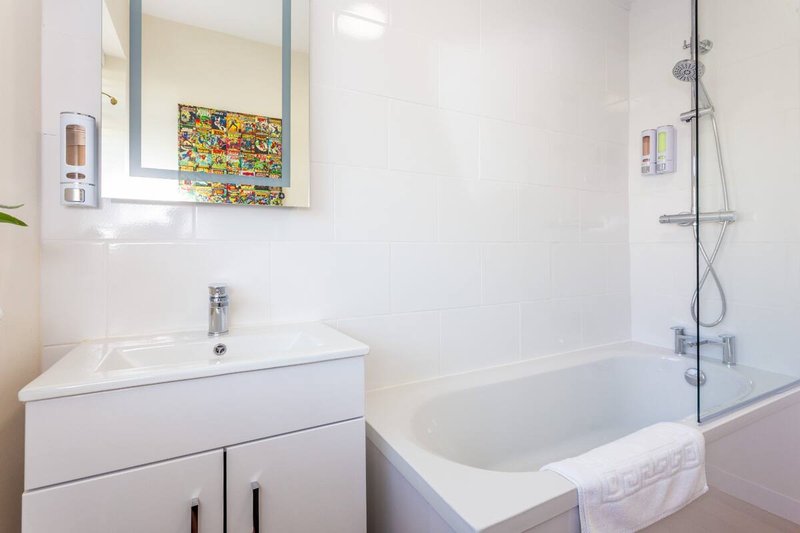 Modern bathroom with white vanity, mirror, bathtub and shower enclosure