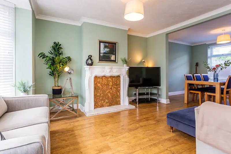 Spacious living room with fireplace, wooden floors, green walls and comfortable seating