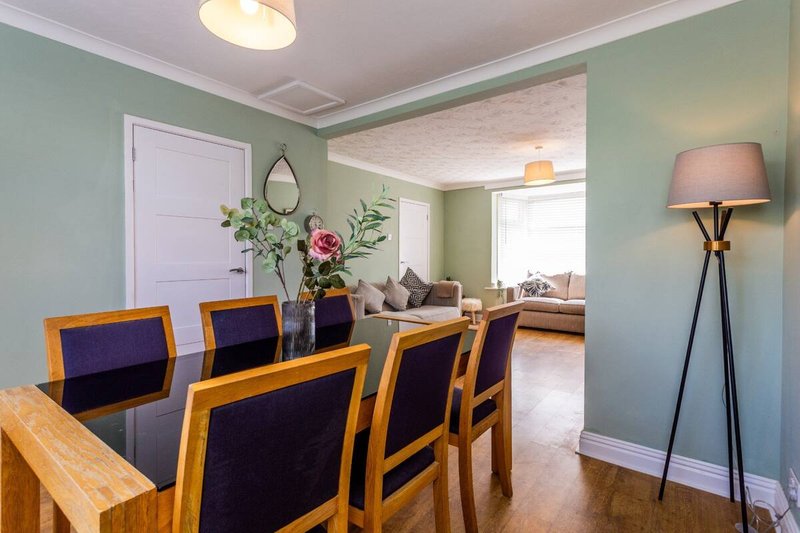 Dining room with wooden table, purple chairs, green walls and floor lamp