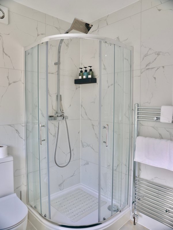 Modern bathroom with marble-effect tiles, curved glass shower enclosure and heated towel rail